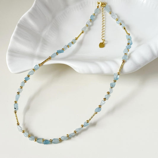 Soft blue natural stone necklace styled on a white dish with gold-plated hardware.