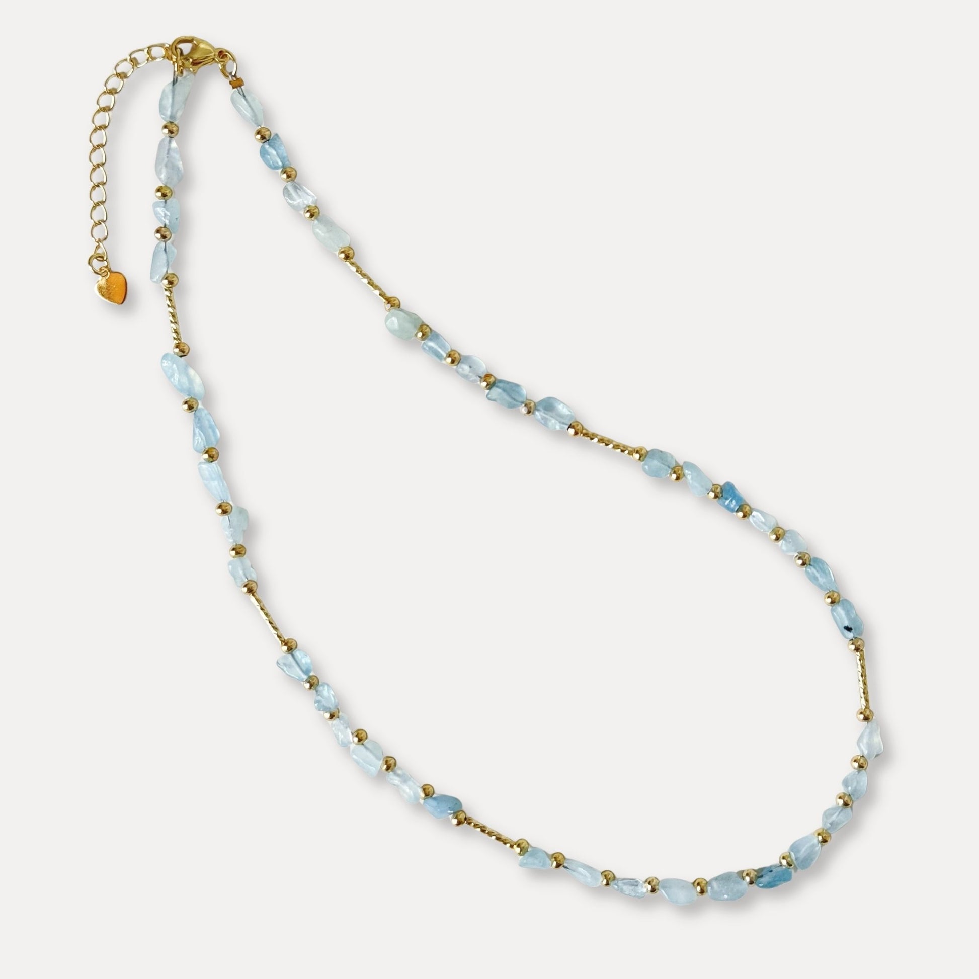 Pale blue natural stone necklace with gold-plated details arranged on a light background.
