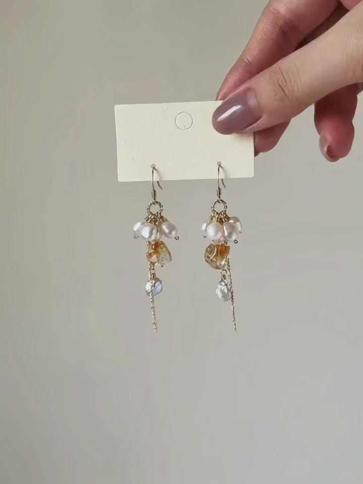 Gleam citrine and freshwater pearl earrings shown from full product display to worn view, highlighting the layered materials and flowing chain movement.