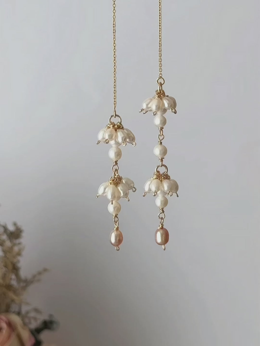 Drift freshwater pearl threader earrings shown suspended and then worn, highlighting the asymmetric pearl clusters and fluid chain movement.