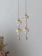 Drift freshwater pearl threader earrings shown suspended and then worn, highlighting the asymmetric pearl clusters and fluid chain movement.