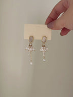Drape freshwater pearl earrings shown from full product display to worn view, highlighting the asymmetric lengths and gentle movement.