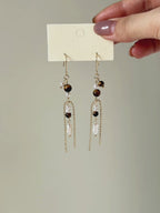 Tether tiger eye and freshwater pearl earrings shown from full product display to worn view, highlighting the long silhouette and fluid movement.