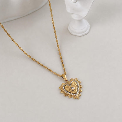 Gold Radiant Heart Pendant Necklace styled beside a white sculptural bust on a soft ivory surface