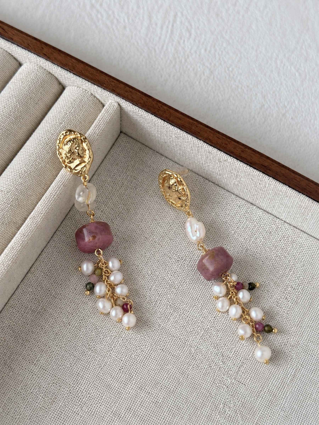 Relic rhodonite and freshwater pearl earrings arranged on a neutral linen jewelry tray.