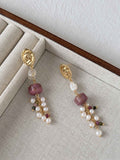 Relic rhodonite and freshwater pearl earrings arranged on a neutral linen jewelry tray.