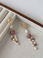 Relic rhodonite and freshwater pearl earrings arranged on a neutral linen jewelry tray.