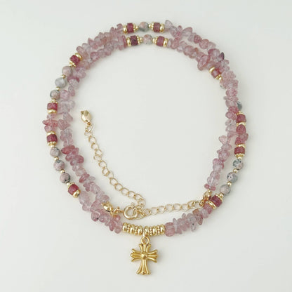 Soft pink stone charm necklace arranged on a clean light background with gold-tone details.