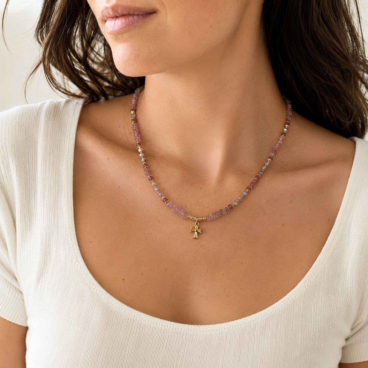 Model wearing a rose-toned strawberry quartz charm necklace with mixed natural stone details.