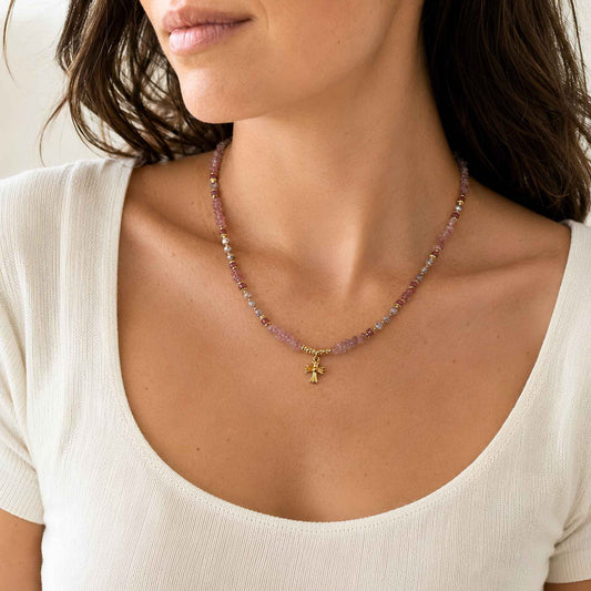 Model wearing a rose-toned strawberry quartz charm necklace with mixed natural stone details.