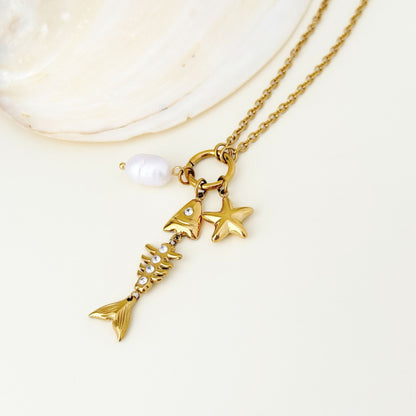 Close-up of sea-inspired gold charms, white bead detail, and small zircon accents.