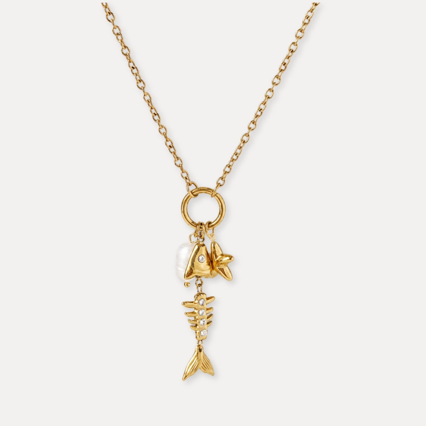 Gold charm necklace with fishbone, fish, starfish, white bead, and zircon details.