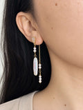 Shift pearl earring worn in its layered two-drop style with a baroque pearl and delicate pearl chain.