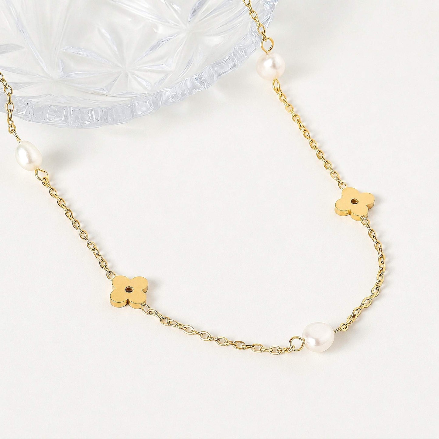 Close-up of freshwater pearls and small gold flower charms on a delicate chain.