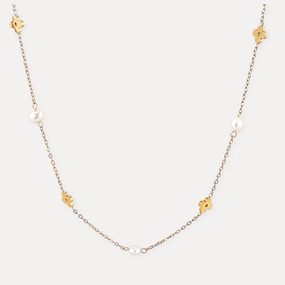 Gold flower necklace with freshwater pearls on a clean light background.