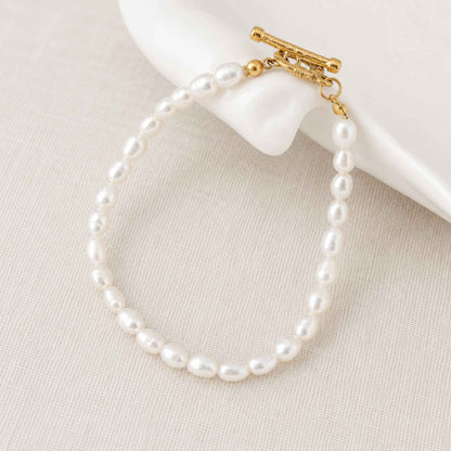 Freshwater pearl bracelet placed on soft linen with a gold toggle clasp.
