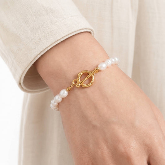 Model wearing a freshwater pearl bracelet with a gold toggle clasp on the wrist.