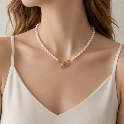 Model wearing a freshwater pearl necklace with a gold toggle clasp and white camisole.