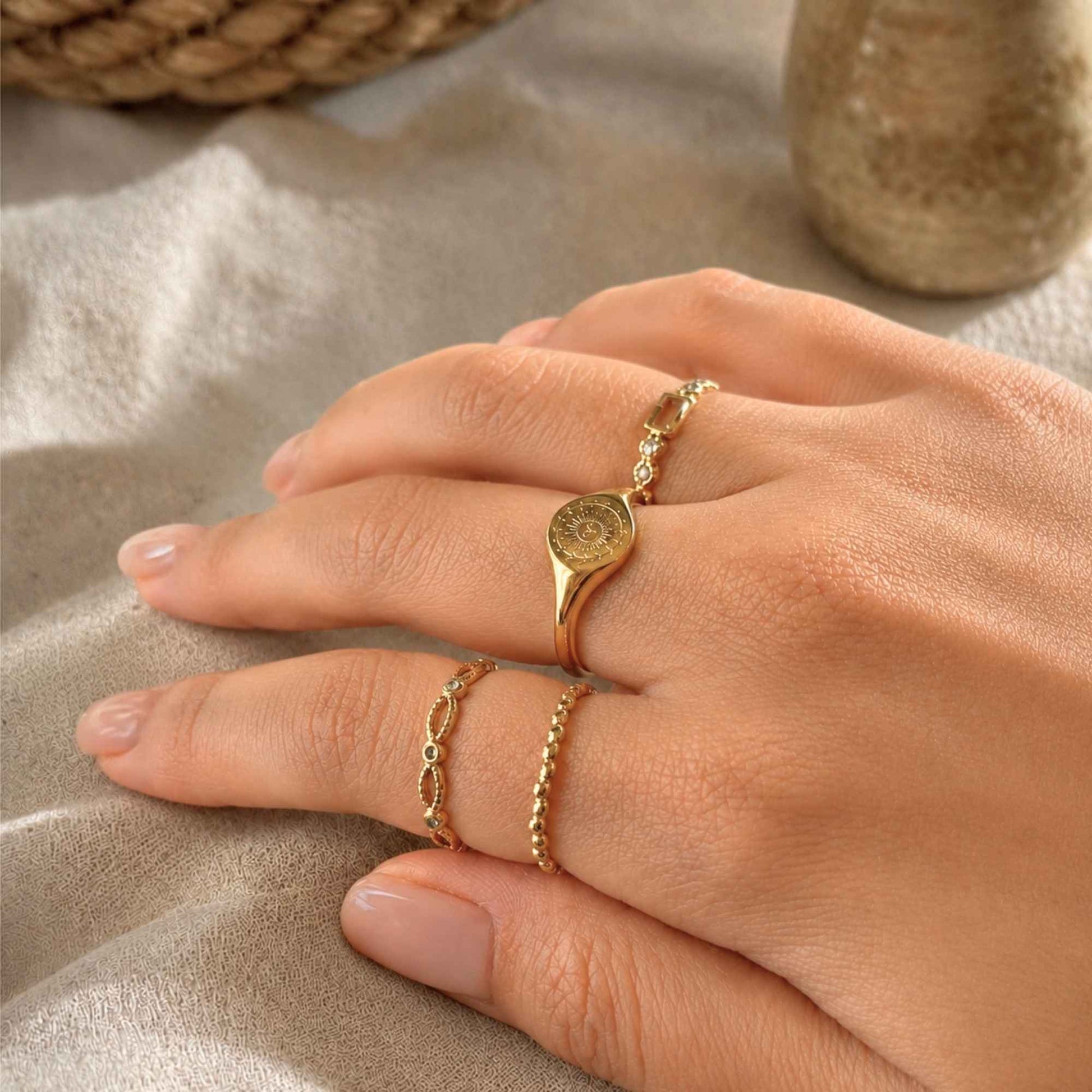 Gold sun signet ring stacked with delicate gold rings