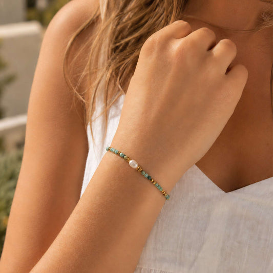 Green natural stone stretch bracelet with freshwater pearl worn on the wrist