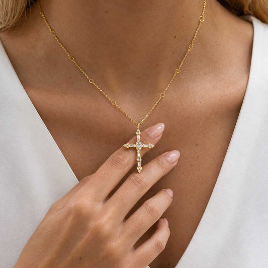 Steadfast Cross Necklace worn with a white V-neck top as the model gently holds the cross pendant