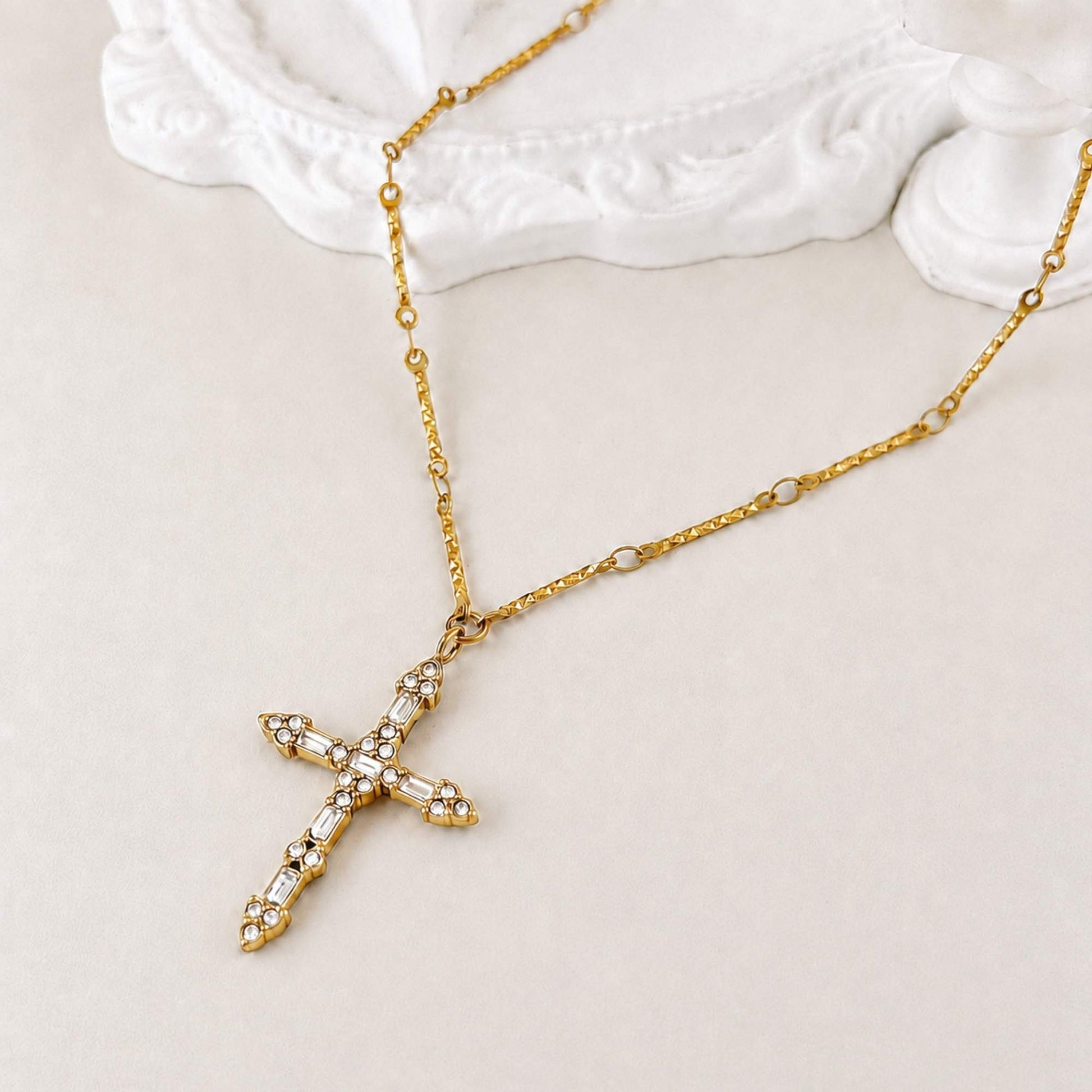 Close-up of the Steadfast gold cross necklace with cubic zirconia and glass details.