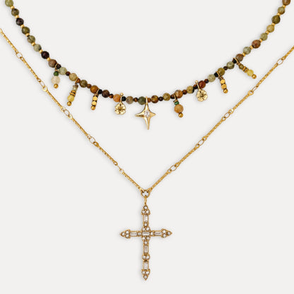 Steadfast Layering Necklace Set with a Tsavorite and Tiger’s Eye necklace layered above a gold cross pendant necklace.