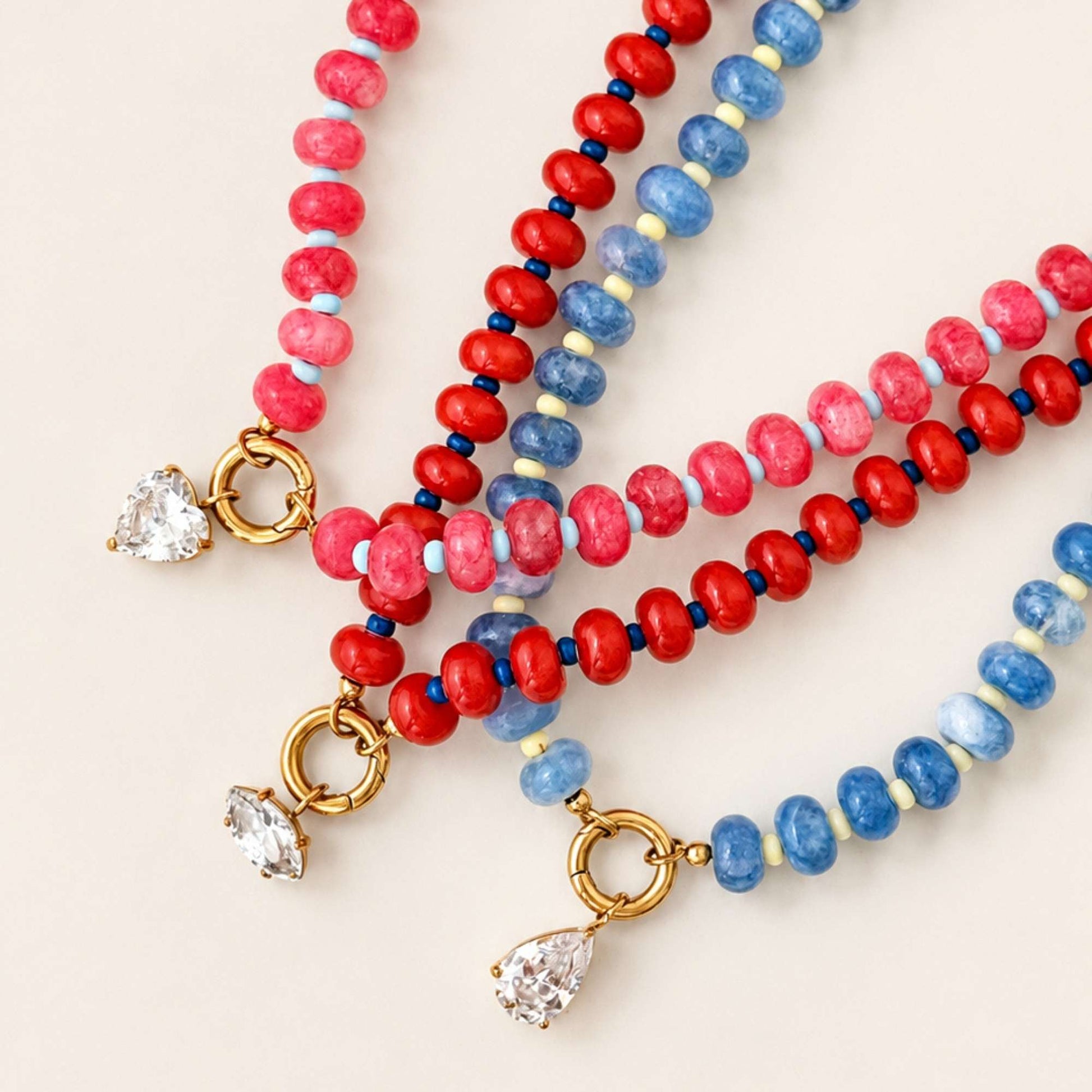 Close-up of colorful natural stone beads with a gold ring and clear zircon charm.