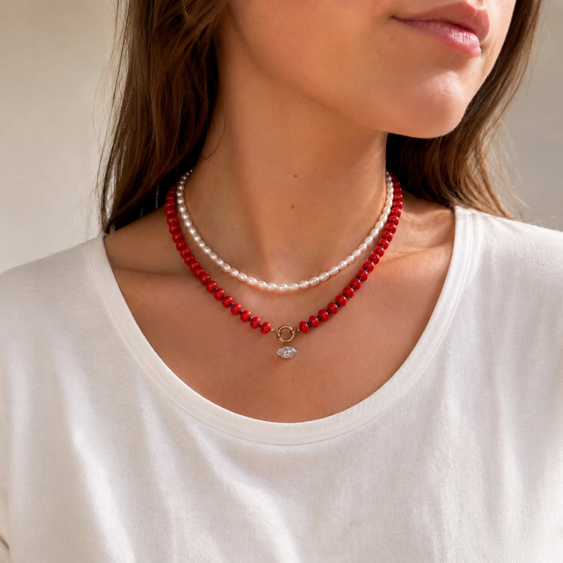 Model wearing a red natural stone beaded necklace with a small zircon drop charm.