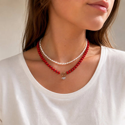 Model wearing a red natural stone beaded necklace with a small zircon drop charm.