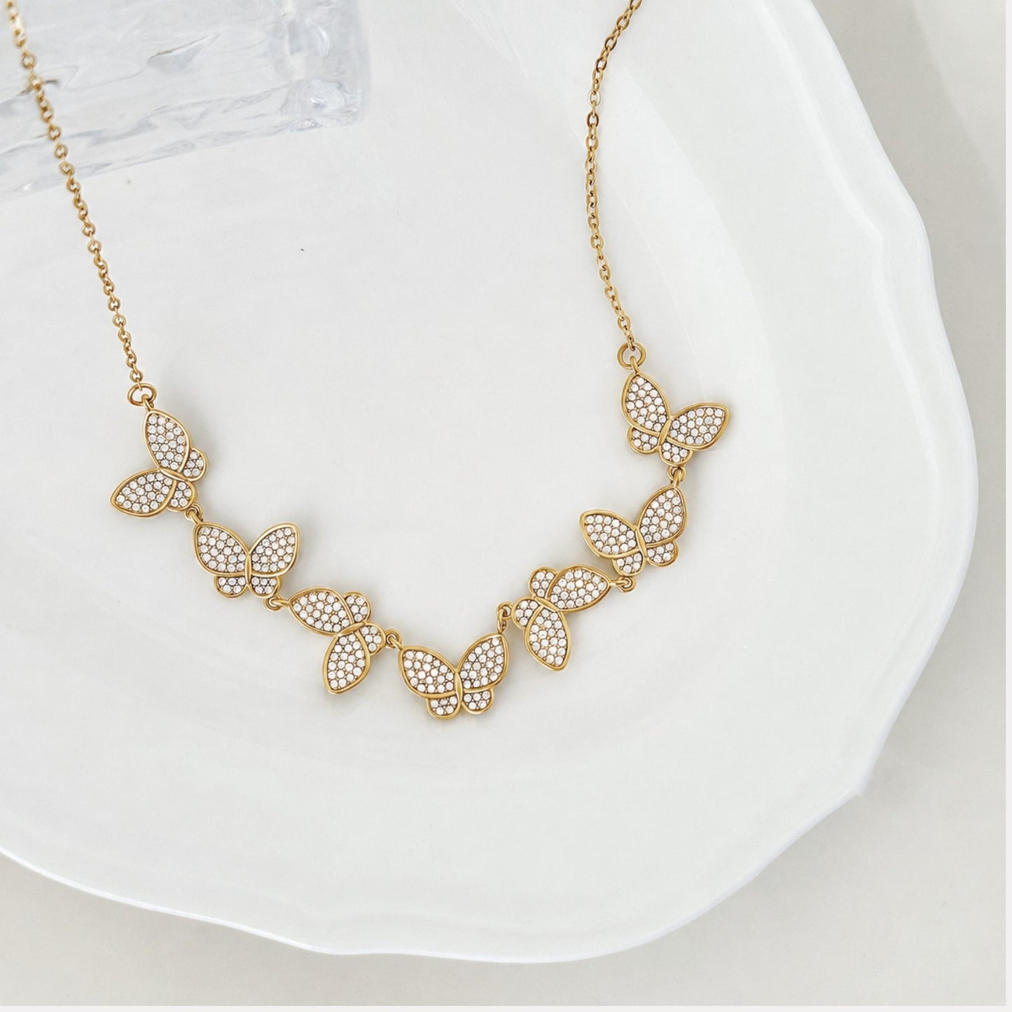 Close-up of gold butterfly details with small zircon stones and delicate chain.