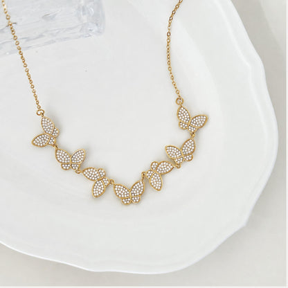 Close-up of gold butterfly details with small zircon stones and delicate chain.