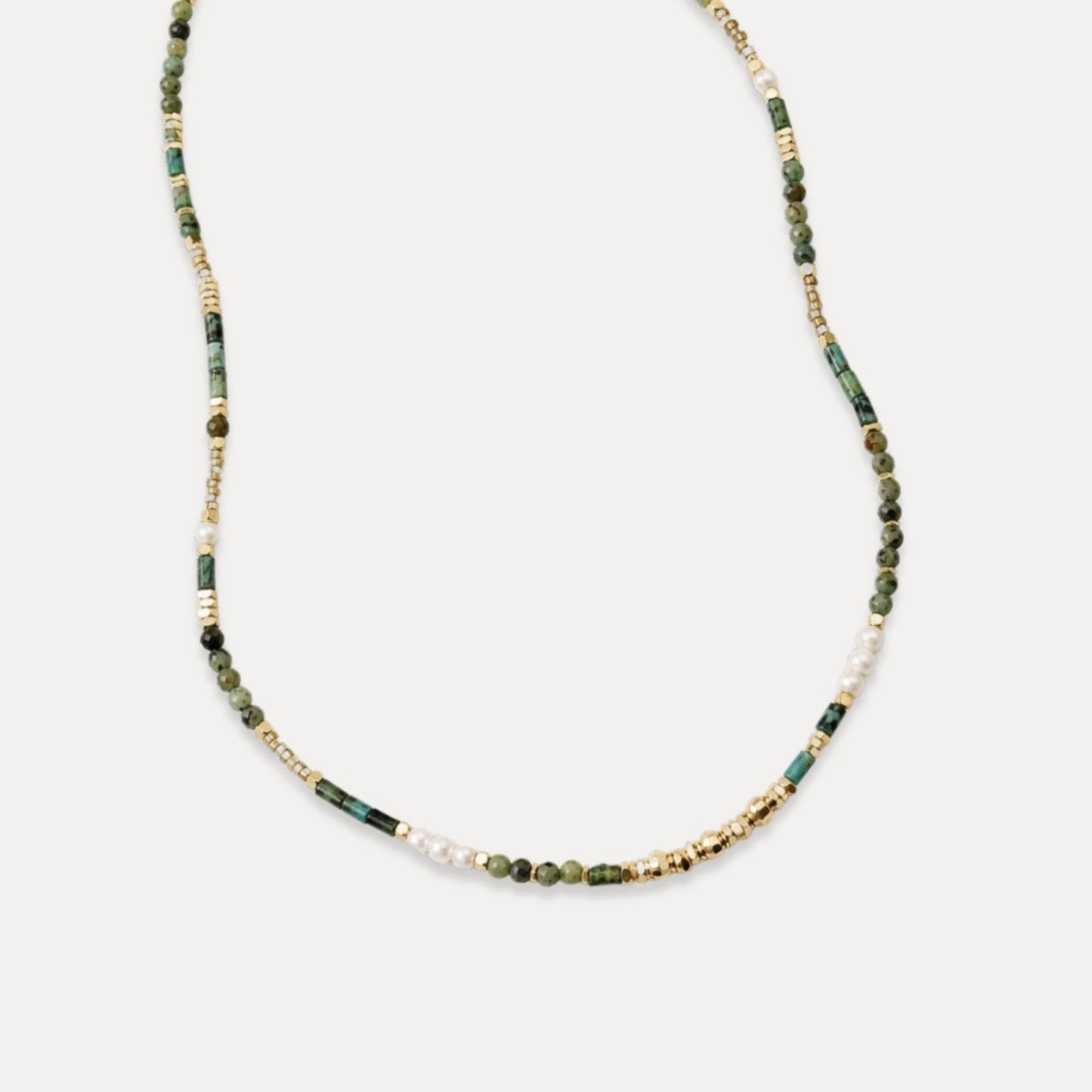 Delicate green stone freshwater pearl and gold beaded necklace on white background