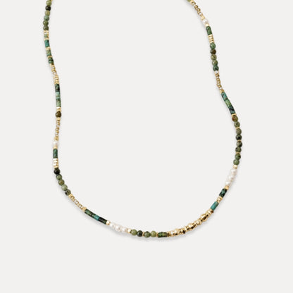Delicate green stone freshwater pearl and gold beaded necklace on white background