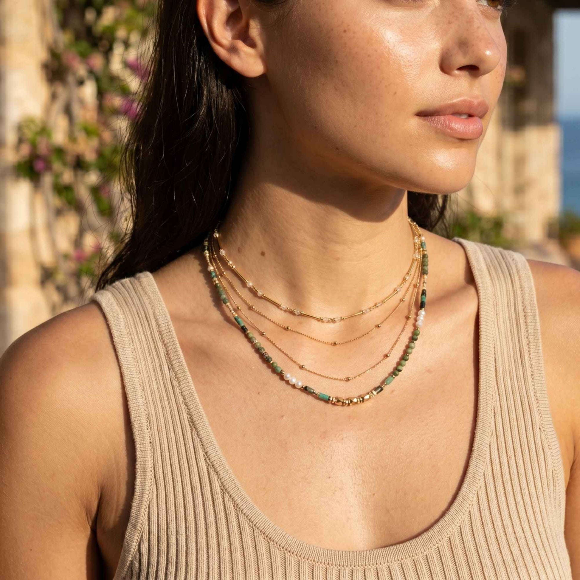 Green natural stone beaded necklace layered with delicate gold necklaces