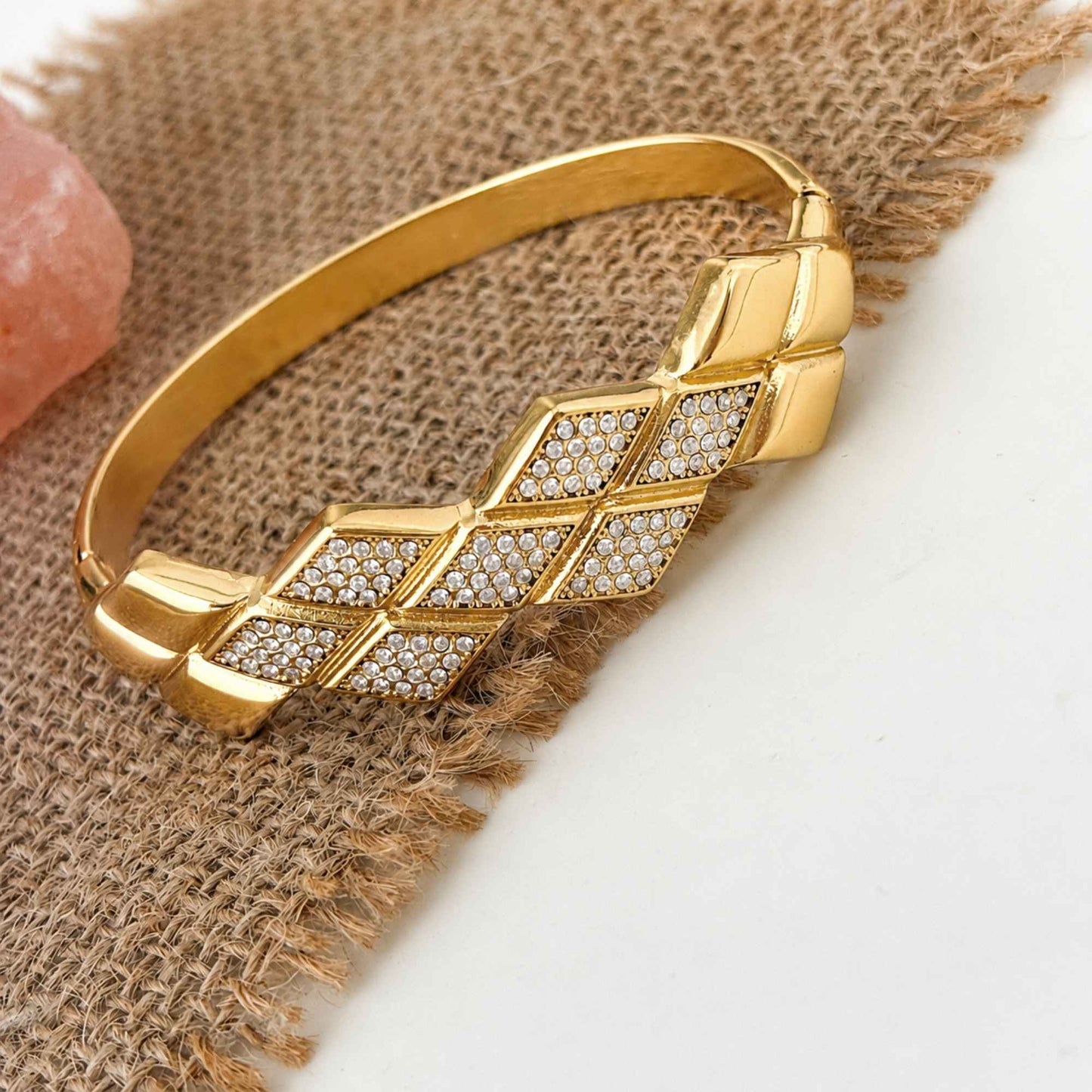 Gold geometric Woven CZ Bangle styled on textured neutral fabric with cubic zirconia panels in focus
