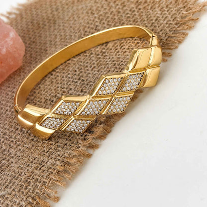Gold geometric Woven CZ Bangle styled on textured neutral fabric with cubic zirconia panels in focus